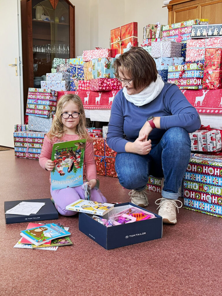 Janet Krusch vom Familienkompass und Marie freuen sich über den Inhalt des Weihnachtsgeschenkes.