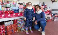 Die fünfjährige Marie und Janet Krusch vom Familienkompass vor den aufgebauten Weihnachtspäckchen.