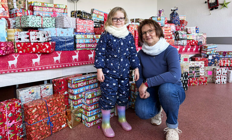 Die fünfjährige Marie und Janet Krusch vom Familienkompass vor den aufgebauten Weihnachtspäckchen.