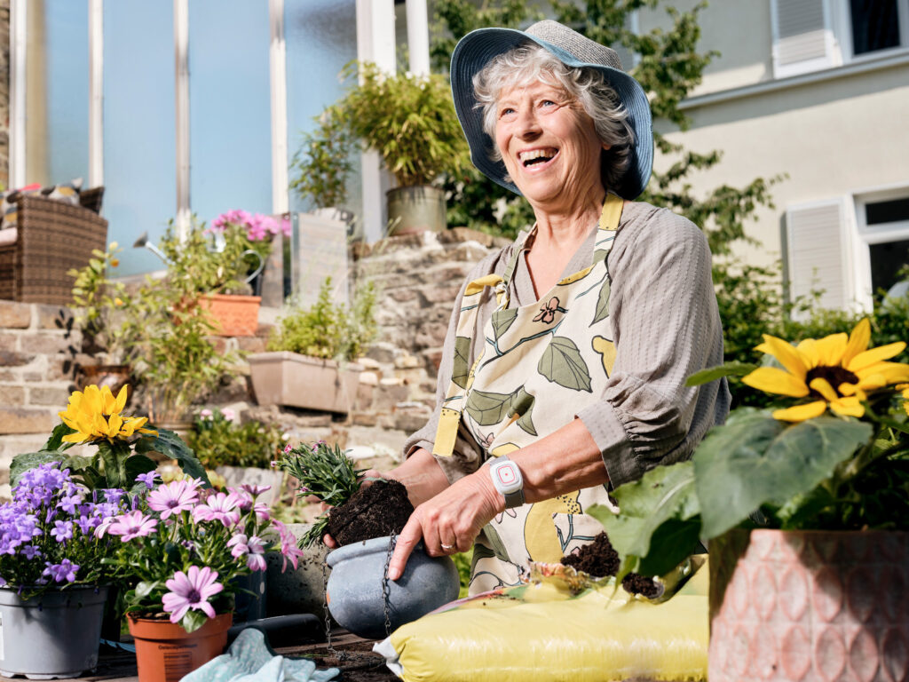 Seniorin mit Hausnotruf Handsender im Garten