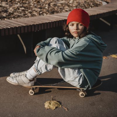 Mädchen sitzt auf Skateboard