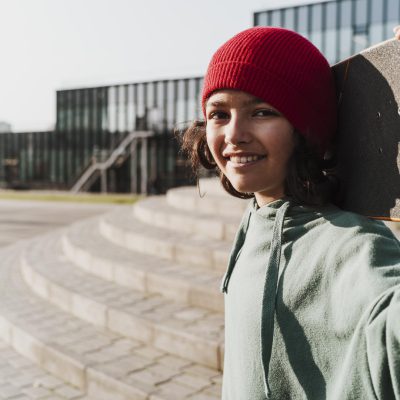 Mädchen mit Skateboard blickt zu Betrachter